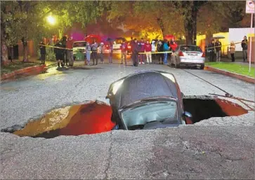  ?? Michael Owen Baker For The Times ?? A CAR sits in a sinkhole on Woodbridge Street near Laurel Canyon Boulevard in Studio City. In Victorvill­e, rescuers found a person dead inside a submerged vehicle, the San Bernardino County Fire Department said.