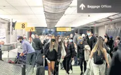  ??  ?? TUSSLE OVER GUIDANCE: Travellers wearing protective face masks reclaim their luggage at the airport in Denver, Colorado, US in November 2020.