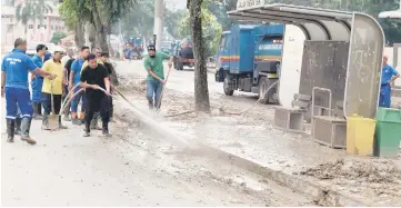  ??  ?? Penang City Council and Petaling Jaya City Council workers cleaning up the mud at the city areas after the massive floods. — Bernama photo