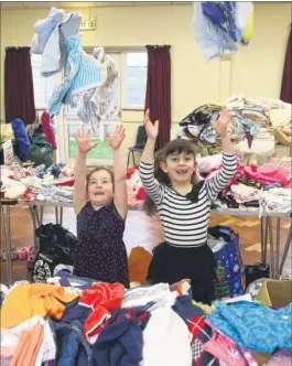  ?? Picture: John Westhrop FM5068182 ?? Hattie Milner, left, with her sister, Erin, help their mum ‘sort out’ the clothes before customers to the Twyford Pre-School jumble sale began in Yalding Village Hall