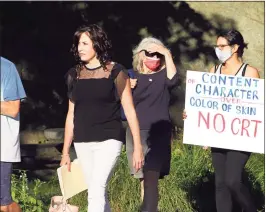  ?? Christian Abraham / Hearst Connecticu­t Media ?? A woman carrying a sign protesting the teaching of critical race theory arrives at a Board of Education meeting at Central Middle School in Greenwich in June.