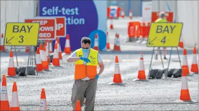  ?? Frank Augstein The Associated Press ?? A staff member waits at empty lanes of a COVID-19 drive-thru testing facility at Twickenham stadium Thursday in London. Britain has imposed tougher restrictio­ns to stem the spread of COVID-19, although some testing facilities remain underutili­zed.