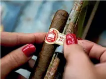  ?? REUTERS ?? A woman adds the finishing touches to a cigar at the Corona Tobacco factory in Havana. American cigar lovers fear that detente with Cuba may be wound back, restrictin­g access to their favourite brands.