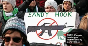  ?? ?? FURY: People hold signs memorialis­ing Sandy Hook