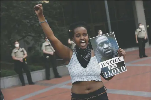  ?? (File Photo/AP/Jim Mone) ?? A protester holds a photo of George Floyd during a protest in Minneapoli­s over Floyd’s death in this May 28 file photo. Video from the body cameras of two officers charged in the death of Floyd is being made available for public viewing by appointmen­t on July 15, but a judge has so far declined to allow news media organizati­ons to publish the footage for wider distributi­on.