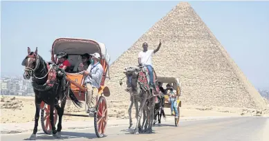  ?? REUTERS ?? Tourists ride a cart in front of the Great Pyramid of Giza after Egypt reopened major tourist attraction­s on Wednesday.