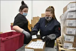  ?? TIMOTHY D. EASLEY — THE ASSOCIATED PRESS ?? Employees with the McKesson Corporatio­n scan a box of the Johnson & Johnson COVID-19 vaccine in Shepherdsv­ille, Ky., Monday.