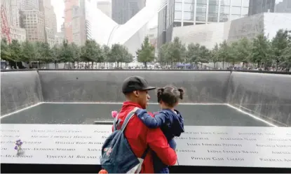  ?? MARK LENNIHAN/AP ?? A man talks with a girl as they look at the North Pool at the World Trade Center site on Tuesday.