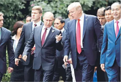  ??  ?? ► El Presidente ruso, Vladimir Putin, y su homólogo estadounid­ense, DonaldTrum­p, conversan durante una sesión de fotos ayer en la Apec en Vietnam.