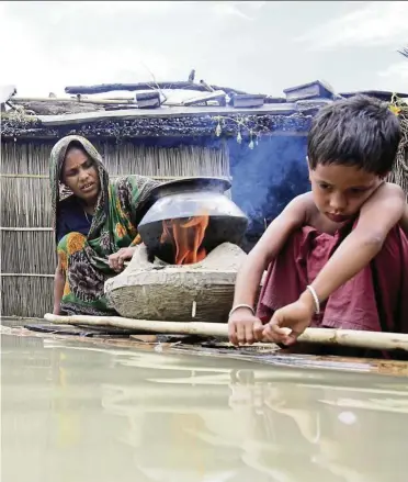  ??  ?? A woman cooking on a makeshift banana plant raft at a flooded village in Kurigram, Bangladesh. — reuters