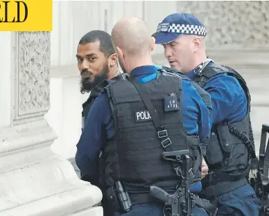  ?? NIKLAS HALLE’N / AFP / GETTY IMAGES ?? British police officers detain a man near Downing Street and the houses of Parliament in central London on Thursday. The man, who was under surveillan­ce after a tip from his family, was carrying a number of knives.