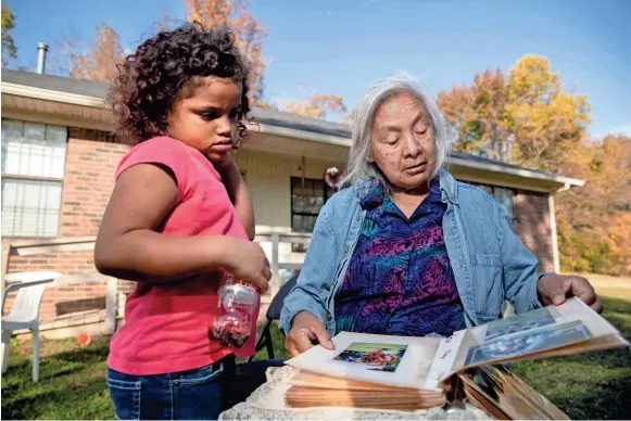  ?? MAX GERSH / THE COMMERCIAL APPEAL ?? Lacie Bell looks through a photo album with her granddaugh­ter, Emani, 4, on Thursday, Nov. 5, 2020, at the Choctaw reservatio­n in Henning.