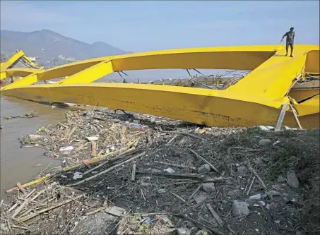  ??  ?? On Thursday a man climbs a bridge destroyed in the massive earthquake and tsunami that hit Palu, Indonesia.