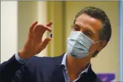  ?? JAE C. HONG — THE ASSOCIATED PRESS FILE ?? On Dec. 14, Gov. Gavin Newsom holds up a vial of the Pfizer-BioNTech COVID-19 vaccine at Kaiser Permanente Los Angeles Medical Center in Los Angeles.