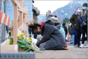  ?? DAVID ZALUBOWSKI / ASSOCIATED PRESS ?? Star Samkus, who works at the King Soopers grocery store and knew the three store employees who were victims in Monday’s mass shooting, kneels before crosses put up for the victims on the edge of the store’s parking lot Tuesday in Boulder, Colo.