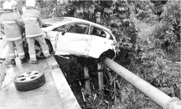  ??  ?? Firemen taking a closer look at the car’s precarious situation.