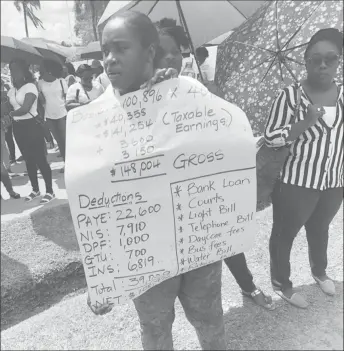  ??  ?? A protestor holds a placard showing the breakdown of a regular teacher’s earnings and spending.