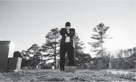  ?? ALLEN G. BREED/AP ?? Mortician Shawn Troy stands at the grave of his father, William Penn Troy Sr., at Hillcrest Cemetery in May outside Mullins, South Carolina.