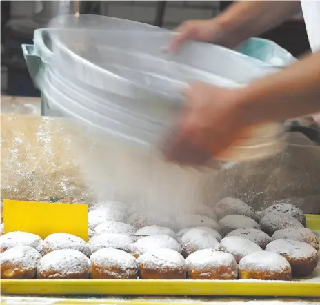  ?? AP FILE PHOTO ?? Paczki, Polish doughnuts with filling, are dusted with sugar at the European Bakery in Jackson, Mich., in 2018.