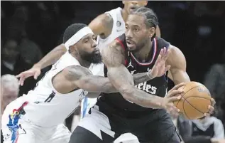  ?? Frank Franklin II Associated Press ?? THE CLIPPERS’ Kawhi Leonard keeps the ball away from the long reach of the Brooklyn Nets’ Royce O’Neale. Leonard scored 24 points and was clutch late in the Clippers’ 124-116 victory.