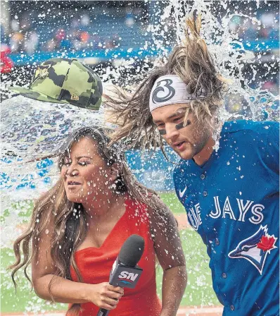  ?? RICK MADONIK TORONTO STAR ?? On a stormy afternoon in the city, Sportsnet’s Hazel Mae and the Jays’ star of the game, Bo Bichette, managed to stay dry at the Rogers Centre — until Vladimir Guerrero Jr. delivered his clockwork post-victory dousing.