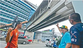  ?? SUNSTAR FOTO / AMPER CAMPAÑA ?? SAFETY MEASURE. Apas Barangay Capt. Ramil Ayuman (2nd from right) points to the defective portion of the skywalk connecting UC Banilad Campus and Gaisano Country Mall.