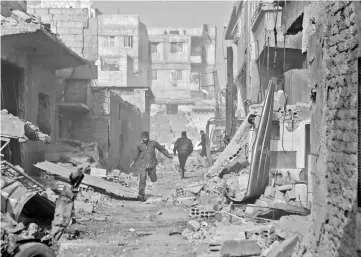  ??  ?? Syrian men run through an alley in the rebel-controlled town of Mesraba, in the eastern Ghouta region on the outskirts of the capital Damascus. — AFP photo