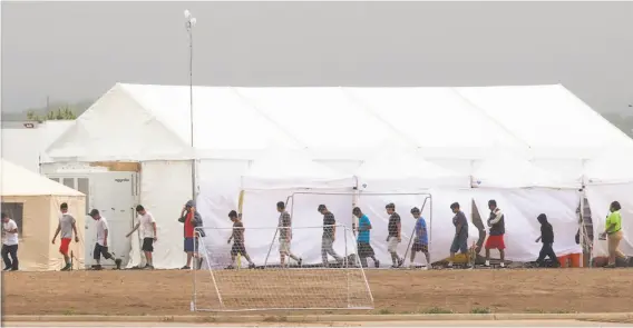  ?? Ivan Pierre Aguirre / for the San Antonio Express-News ?? Immigrant children walk past tents at a Customs and Border Protection facility in Tornillo, Texas, where they are being held after crossing into the U.S. illegally.