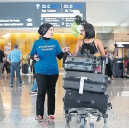  ?? STEVE RUSSELL TORONTO STAR ?? Alaa Alobaidy, left, working at a Destinatio­n Ontario kiosk, assists Marcela Servellon, an arrival from El Salvador, at Pearson Internatio­nal Airport.