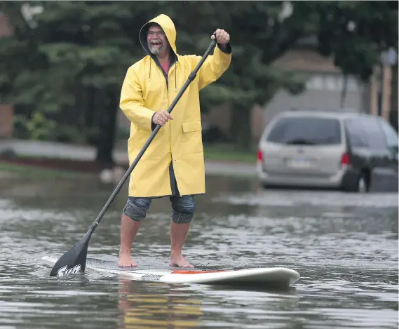  ?? JASON KRYK ?? Dave Severs floats down Kimberly Drive in Tecumseh on Thursday after heavy rains led to flooding in the area.