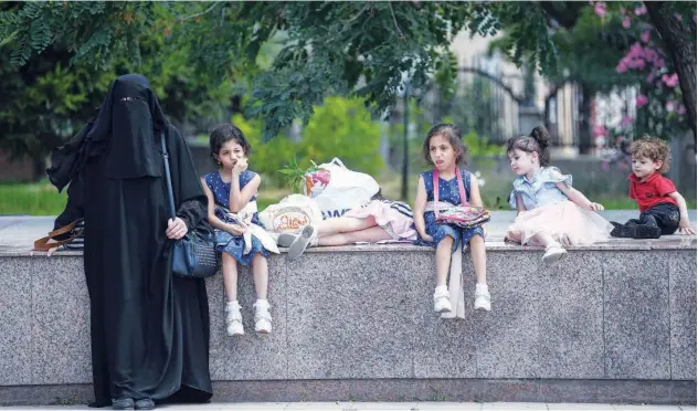  ?? Agence France-presse ?? ↑ A Syrian woman and her children wait to board a bus in the Esenyurt district in Istanbul.