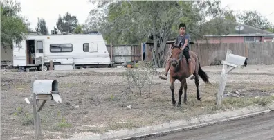  ?? Fotos de Eric Gay / AP ?? Un niño monta a caballo en la colonia Indian Hills East cerca de Alamo, Texas, el 12 de julio de 2017. Al fondo se ve una casa rodante desmejorad­a, típica de estos barrios pobres cercanos a la frontera con México.