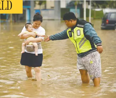  ?? NOEL CELIS / AFP VIA GETTY IMAGES ?? People wade down a flooded street following a heavy rain on Thursday in Zhengzhou, in China's Henan province.