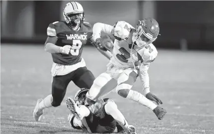  ?? GRUENKE/STAFF JONATHON ?? Hampton’s Aiden Gibson is tripped up by Warwick’s Nashaun Toye during Tuesday night’s high school football game at Todd Stadium.