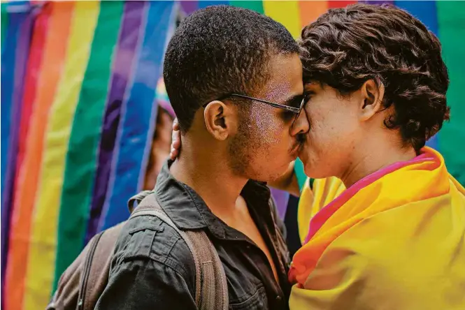  ?? Eduardo Anizelli/ Folhapress ?? Purpurinad­os, casal se beija na 22ª Parada do Orgulho LGBT de São Paulo, que levou multidão às ruas da cidade