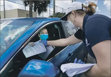  ?? Matias J. Ocner Miami Herald ?? CITY EMPLOYEE Tatiana Fernandez hands out unemployme­nt insurance forms in Hialeah, Fla. In March, states issued new jobless benefits to 1.7 million people, just a fraction of the 12 million who filed new claims.