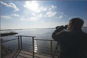  ?? NWA Democrat-Gazette/FLIP PUTTHOFF ?? Joe Neal scans Kerr Reservoir, a pool of the Arkansas River. The wildlife refuge is spread out on both sides of the river.