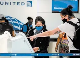 ?? MARIO TAMA/GETTY ?? A United Airlines employee wears a required face covering at check-in at Los Angeles Internatio­nal Airport.
