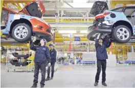  ?? — Reuters ?? Employees install car components at an assembly line at a Ford manufactur­ing plant in Chongqing municipali­ty, in central China.