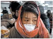  ?? KEVIN FRAYER/GETTY ?? A Chinese woman wears a mask to help guard against coronaviru­s as she shops Thursday at a market in Beijing.