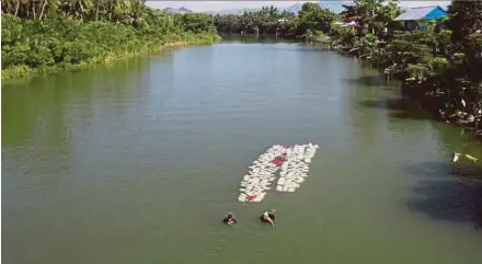  ?? PIC AFP ?? Two women swimming back to their village with jars of clean water in Tinambung on Wednesday.