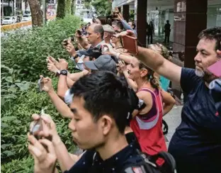  ?? (CHRIS MCGRATH/GETTY IMAGES)) ?? A Singapour, de nombreux badauds ont immortalis­é l’arrivée de Kim Jong-un.