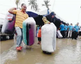  ??  ?? ... Kampung Permatang Rawa flood victims receiving mattresses from Rural and Regional Developmen­t Ministry officials in the compound of the Permatang Rawa Kemas kindergart­en yesterday. They are among thousands who were affected by the rainstorm that...