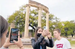  ?? THANASSIS STAVRAKIS/AP ?? Students use a mobile app Wednesday at the ancient site of Olympia in Greece. The app provides virtual recreation­s of temples and competitio­n areas.