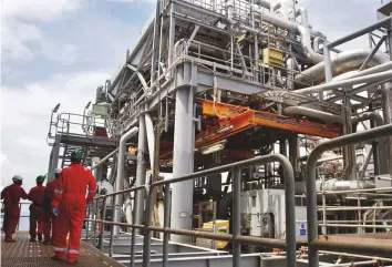  ?? Reuters ?? Oil workers walk through pipe installati­ons on a tanker at the Bonga off-shore oil field outside Lagos, Nigeria. Oil prices are currently trending at a four-year high of above $82 a barrel.