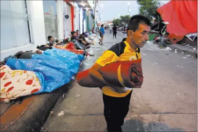  ?? Moises Castillo ?? A Central American migrant traveling with a caravan to the U.S. holds his bedroll Tuesday in Huixtla, Mexico. The Associated Press