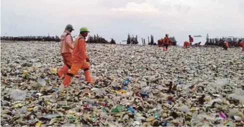  ??  ?? PETUGAS berjalan di atas timbunan sampah yang dikumpul di Muara Angke di Teluk Jakarta ketika operasi pembersiha­n dilakukan. - Agensi