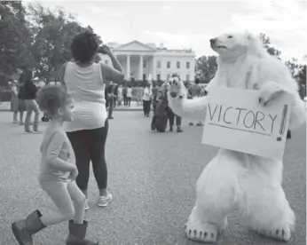  ?? MARK WILSON/GETTY IMAGES ?? A young girl checks out high-fiving climate control activist Catherine Kilduff, dressed as a polar bear, after U.S. President Barack Obama announced on Friday that he would reject Keystone XL.