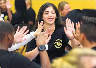  ?? GARY MIDDENDORF/DAILY SOUTHTOWN PHOTOS ?? Nada Hinnawi, a sophomore at Richards High School, gets high-fives from her group at a Challenge Day class on positivity and encouragem­ent Tuesday at Richards High School in Oak Lawn.