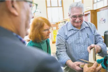  ?? Photos by Santiago Mejia / The Chronicle ?? Webb Johnson (right) and his cousin Judy Wells return the book “Forty Minutes Late” to City Librarian Luis Herrera at the San Francisco Public Library Park Branch. The book had a due-date stamp of 1917.